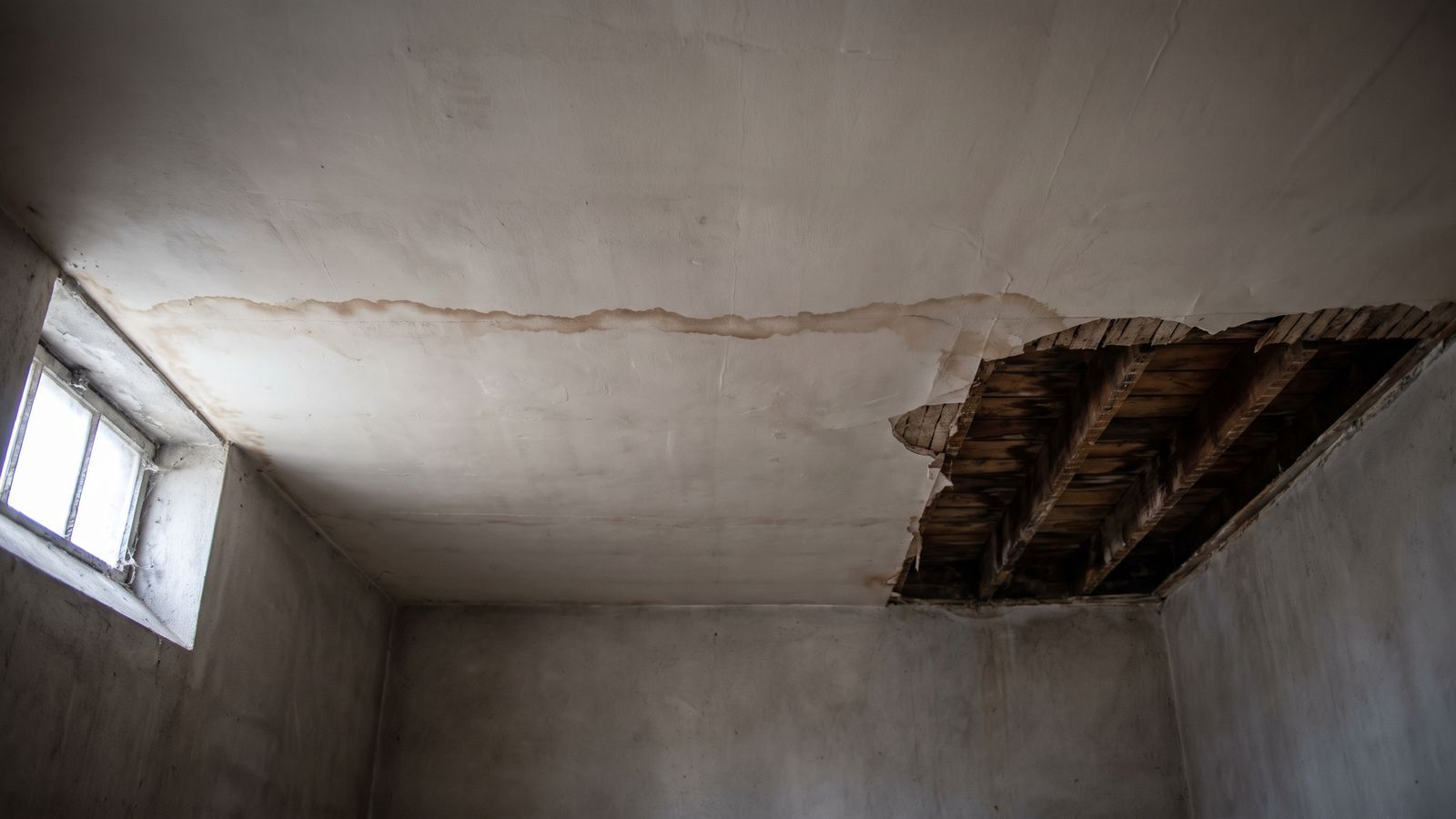 Stained basement ceiling opened to wet joists Brown tide line on a basement ceiling opened to wet joists after a cast iron pipe failure in a DC row house