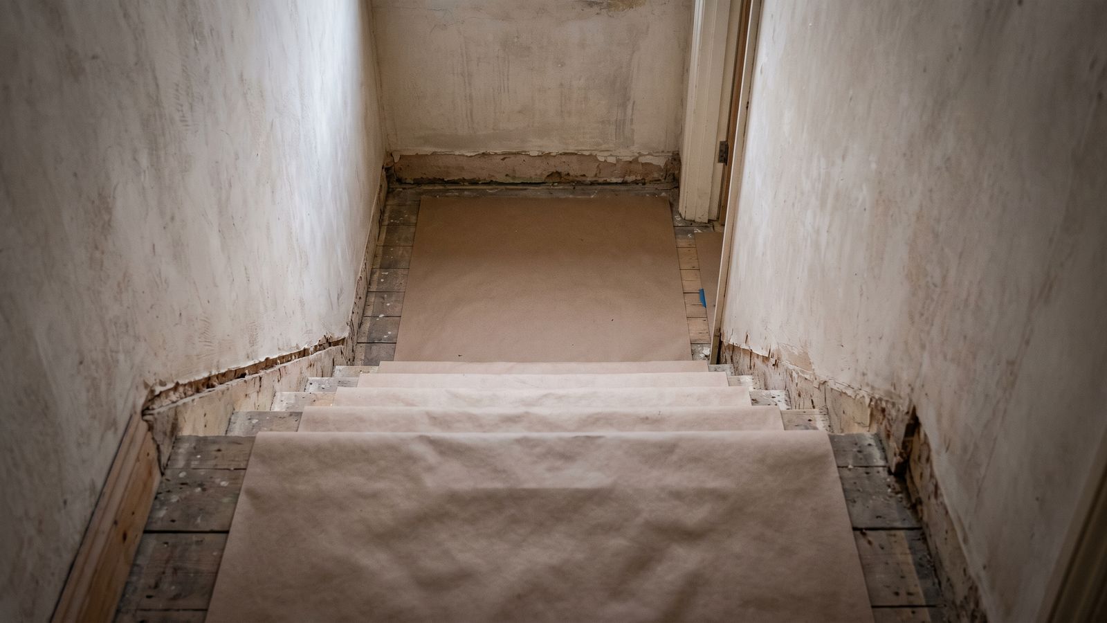 Work in progress, under review A row-house stair landing with the baseboard removed and the treads covered in protective board