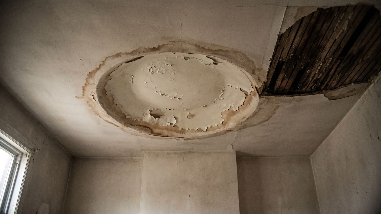 Sagging plaster ceiling with a brown tide ring Sagging plaster ceiling with a brown tide ring, one corner cut open to damp lath after water damage above