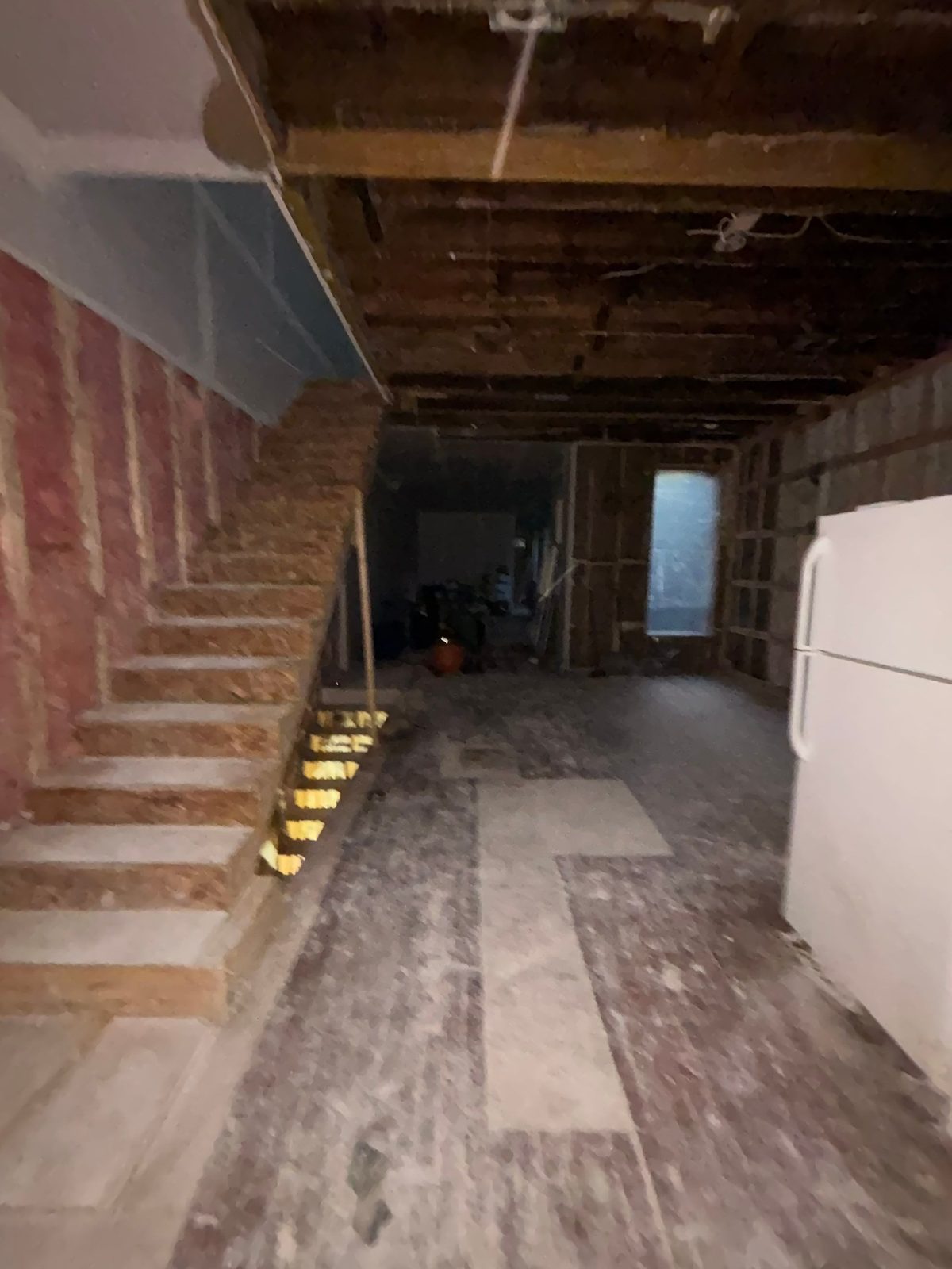 Stair with bare wood treads beside an opened wall with insulation in a rowhouse in Washington, DC, September 2026